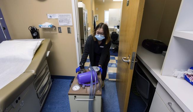 Lab assistant Sydni Hanson transports a suction machine into a patient room, Thursday, July 7, 2022, at WE Health Clinic in Duluth, Minn. Minnesota recorded a 20% jump in abortions in 2022, partly because more patients are traveling from states that have banned or limited the procedure since the U.S. Supreme Court overturned Roe v. Wade, according to an annual report released Friday, June 30, 2023. (AP Photo/Derek Montgomery) **FILE**
