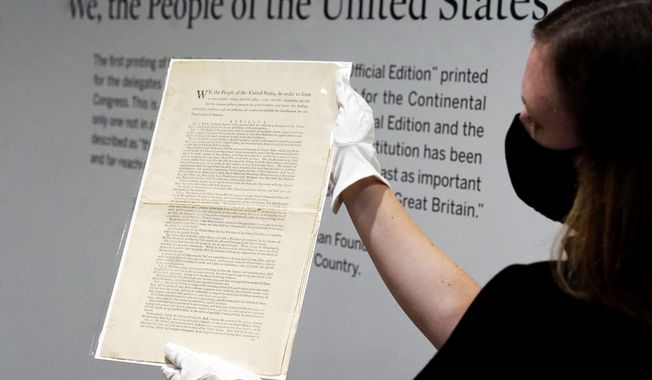 Ella Hall, a specialist in Books and Manuscripts at Sotheby&#x27;s, in New York, holds a 1787 printed copy of the U.S. Constitution, Friday, Sept. 17, 2021. Sotheby&#x27;s announced Friday — appropriately on Constitution Day — that in November it will put up for auction one of just 11 surviving copies of the Constitution from the official first printing produced for the delegates to the Constitutional Convention and for the Continental Congress. It&#x27;s the only copy that remains in private hands and has an estimate of $15 million-$20 million. (AP Photo/Richard Drew)