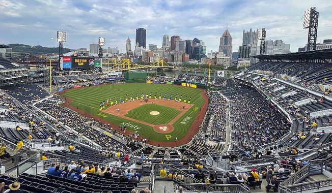The city skyline is visible behind the center field wall as players, family and representatives of late players are seated on the outside edge of the infield at PNC Park near the number and banners of the Pittsburgh Pirates players that are part of the first team Hall of Fame class during a ceremony before a baseball game between the Pirates and the Toronto Blue Jays, Saturday, Sept. 3, 2022, in Pittsburgh. (AP Photo/Keith Srakocic)