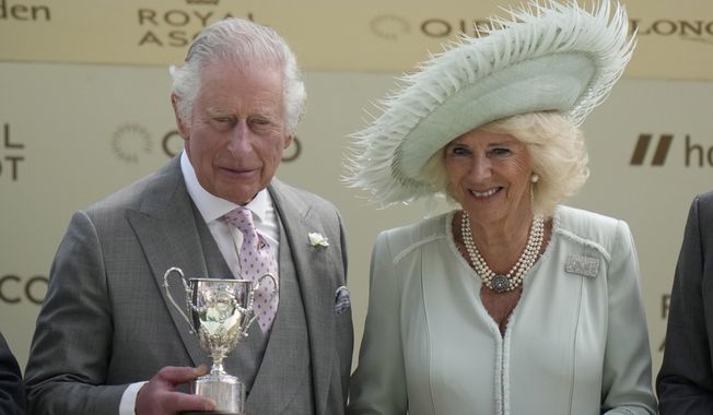 Britain&#x27;s King Charles III holds a trophy standing beside Camilla, the Queen Consort during Ladies Day of the Royal Ascot horse racing meeting, at Ascot Racecourse in Ascot, England, Thursday, June 22, 2023.(AP Photo/Alastair Grant)