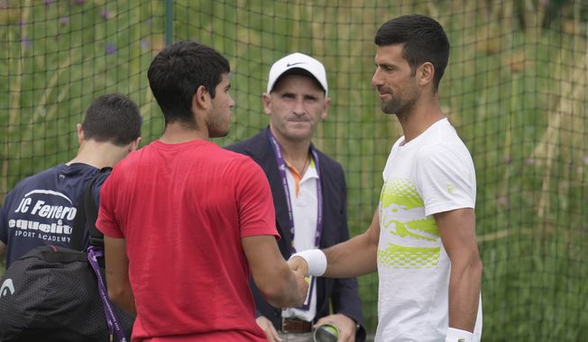 Novak Djokovic of Serbia, right, and Carlos Alcaraz of Spain shake hands as they meet during a practice session ahead of the Wimbledon tennis championships at Wimbledon, in London, Sunday, July 2, 2023. The Wimbledon Tennis championships start on July 3. (AP Photo/Kin Cheung) **FILE**