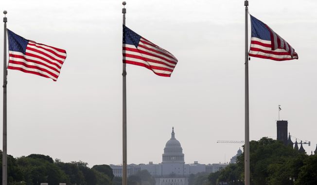 American flags fly with a cloudy sky above the U.S. Capitol in Washington, Friday, June 9, 2023. While the air quality remains unhealthy, the record smoke pollution from wildfires in eastern Canada this week has diminished significantly over the nation&#x27;s capital. (AP Photo/Jose Luis Magana)