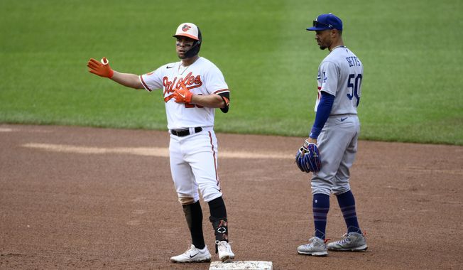 Baltimore Orioles&#x27; Ramon Urias, left, gestures as he stands on second after hitting a double during the third inning of a baseball game next to Los Angeles Dodgers second baseman Mookie Betts (50), Wednesday, July 19, 2023, in Baltimore. (AP Photo/Nick Wass)