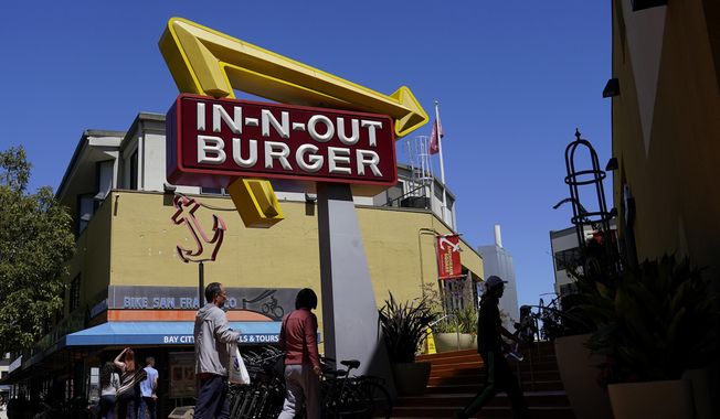 People walk below an In-N-Out Burger restaurant sign in San Francisco, Thursday, Aug. 25, 2022. (AP Photo/Jeff Chiu, File)