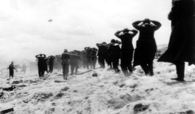 FILE - German prisoners of war are led away by Allied forces from Utah Beach, near Sainte-Mere-Eglise, on June 6, 1944, during landing operations at the Normandy coast, France. The D-Day invasion that helped change the course of World War II was unprecedented in scale and audacity. Veterans and world dignitaries are commemorating the 79th anniversary of the operation. (AP Photo, File)