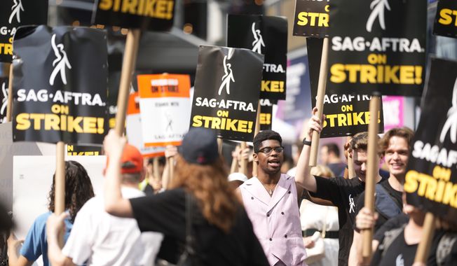 Picketers carry signs outside Paramount in Times Square on Monday, July 17, 2023, in New York. The actors strike comes more than two months after screenwriters began striking in their bid to get better pay and working conditions and have clear guidelines around the use of AI in film and television productions. (Photo by Charles Sykes/Invision/AP)