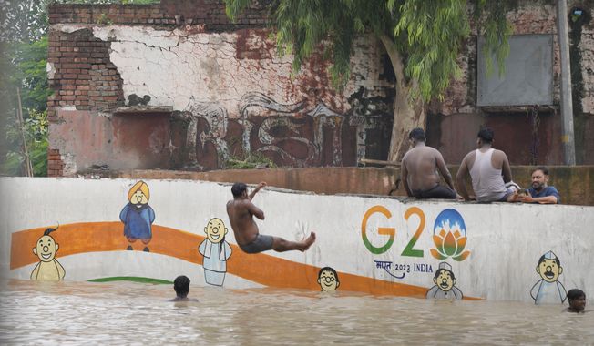 People living along the banks of the river Yamuna sit at a flooded underpass in New Delhi, India, Thursday, July 13, 2023. (AP Photo/Manish Swarup)