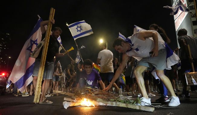 Israelis light a bonfire as they protest against plans by Prime Minister Benjamin Netanyahu&#x27;s government to overhaul the judicial system, in Tel Aviv, Israel, Tuesday, July 18, 2023. (AP Photo/Ariel Schalit)