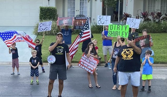 In this photo provided by former Sarasota County School Board Chair Shirley Brown, Proud Boy member James Hoel and others gather outside her home for an anti-mask protest on Oct. 4, 2021. &amp;quot;We see you in there, Shirley. We want you to come out for a redress of grievances,&amp;quot; Hoel said through a megaphone. (Shirley Brown via AP)