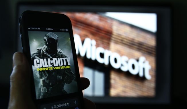 File - An image from Activision&#x27;s Call of Duty is shown on a smartphone near a photograph of the Microsoft logo in this photo taken in New York, Thursday, June 15, 2023. A judge handed Microsoft a big victory on Tuesday, declining to stop its $69 billion takeover of video game maker Activision Blizzard. (AP Photo/Peter Morgan, File)