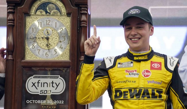 Christopher Bell (20) poses with the trophy in Victory Lane after winning a NASCAR Cup Series auto race at Martinsville Speedway, Sunday, Oct. 30, 2022, in Martinsville, Va. Joe Gibbs Racing driver Christopher Bell turned the fastest qualifying lap of 124.781 mph at New Hampshire Motor Speedway and will lead the field to green for the NASCAR Cup race on Sunday, July 16, 2023.(AP Photo/Chuck Burton, File) **FILE**