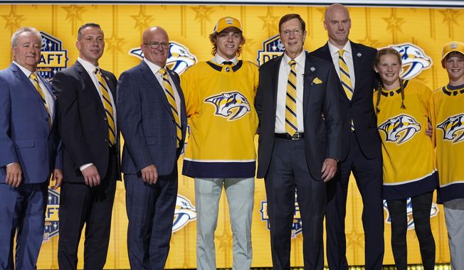 Tanner Molendyk, center left, poses with Nashville Predators officials after being picked by the team during the first round of the NHL hockey draft Wednesday, June 28, 2023, in Nashville, Tenn. (AP Photo/George Walker IV)