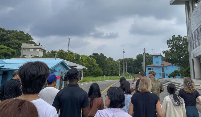 A group of tourists stand near a border station at Panmunjom in the Demilitarized Zone in Paju, South Korea, Tuesday, July 18, 2023. Not long after this photo was taken, Travis King, a U.S. soldier, bolted across the border and became the first known American detained in the North in nearly five years. (AP Photo/Sarah Jane Leslie)