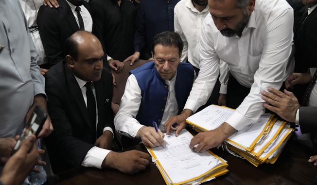 Pakistan&#x27;s former Prime Minister Imran Khan, sign documents as he submits surety bond over his bails in different cases at an office of Lahore High Court in Lahore, Pakistan, Tuesday, July 18, 2023. (AP Photo/K.M. Chaudary)