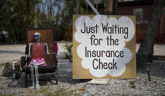 A skeleton in sunglasses sits beside a sign reading: &quot;Just waiting for the insurance check,&quot; outside the closed Kona Kai Motel on Sanibel Island, Fla., Thursday, May 11, 2023. Struggles continue for thousands in Florida months after Hurricane Ian. (AP Photo/Rebecca Blackwell) ** FILE **
