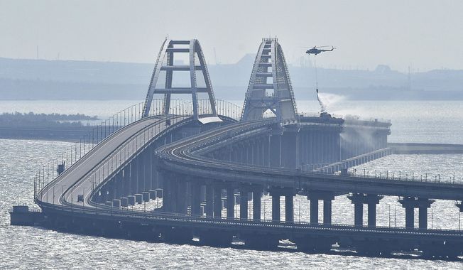 A helicopter drops water to stop fire on the Crimean Bridge connecting Russian mainland and Crimean peninsula over the Kerch Strait, in Kerch, Crimea, Oct. 8, 2022. Russian authorities say a truck bomb has caused a fire and the collapse of a section of a bridge linking Russia-annexed Crimea with Russia. The bridge is a key supply artery for Moscow&#x27;s faltering war effort in southern Ukraine. (AP Photo/File)