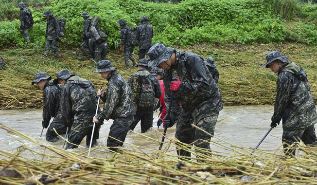 South Korean marines search for missing people in floodwaters in Yecheon, South Korea, Tuesday, July 18, 2023. Rescuers continued their searches Tuesday for people still missing in landslides and other incidents caused by more than a week of torrential rains. (Lee Moo-ryul/Newsis via AP)