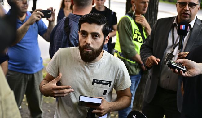 A man talks to the media outside the Isaeli embassy in Stockholm, Sweden, July 15, 2023. The man who said he would burn the Torah and the Bible outside the Israeli Embassy in Stockholm gave up his plan and instead held a one-person demonstration against burning holy books. (Magnus Lejhall/TT News Agency via AP)
