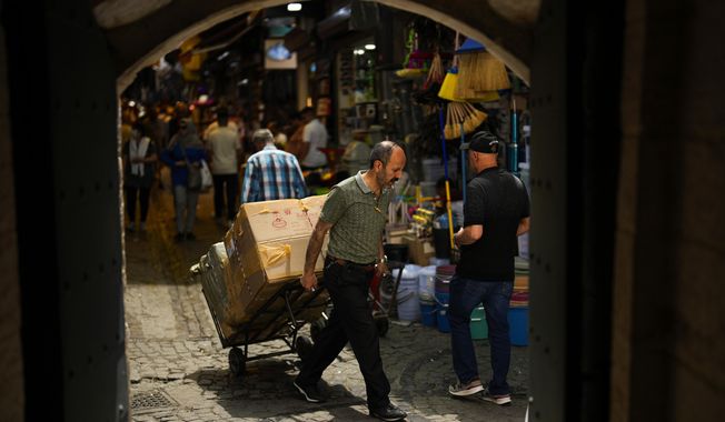 A man pulls a trolley with goods in a street market in Eminonu commercial district in Istanbul, Turkey, Friday, June 16, 2023. The Turkish central bank faces a key test Thursday June 22, 2023, on turning to more conventional economic policies to counter sky-high inflation after newly reelected President Recep Tayyip Erdogan gave mixed signals about an approach that many blame for worsening a cost-of-living crisis. (AP Photo/Francisco Seco)